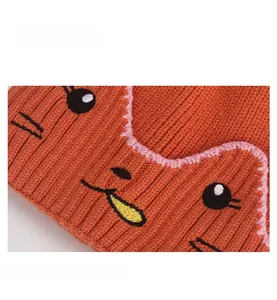Détail du bonnet en tricot côtelé orange pour bébé avec broderie visage d'animal