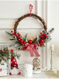 Detail of red berry Christmas wreath with warm LED lights and a striped bow on wooden vine