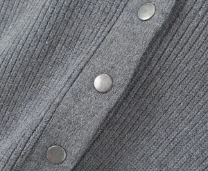 Macro detail of grey ribbed knit texture and vintage metal buttons on the cardigan
