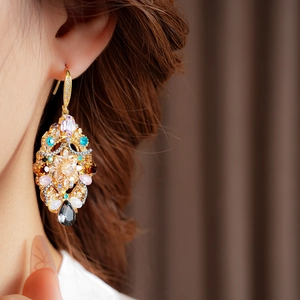 Close-up of vintage gold earrings with multi-colored crystals worn by a model