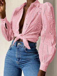 Detailed view of pink eyelet embroidery fabric and front tie knot on long sleeve shirt