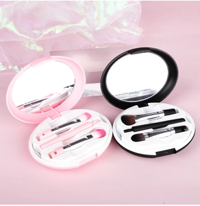 Close-up of portable makeup brush set with built-in mirror and pink gradient bristles