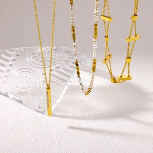 Three gold and silver geometric minimalist necklaces shown with elegant glass decor