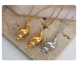 Macro view of polished gold and silver conch shell pendants on minimalist bead chains