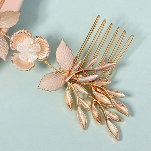 Close-up of golden bridal hair comb with enamel pink flowers and pearl accents
