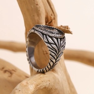Macro detail of retro silver feather textures and animal totem on the stainless steel ring