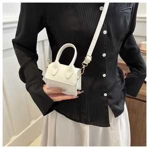Detailaufnahme einer weißen Mini-Handtasche aus PU-Leder mit goldenen Metallbeschlägen
