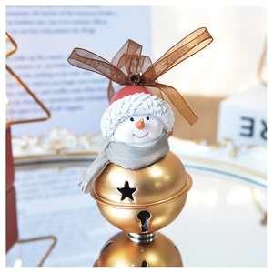 Detail of resin snowman ornament with gold bells and dark brown silk ribbon on mirror