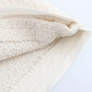 Close-up of beige tweed woven fabric showing detailed texture and high-quality stitching