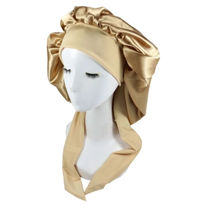 Detail of champagne satin sleep bonnet with long ties on a mannequin head