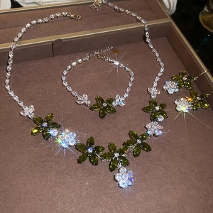 Detail of luxury silver necklace set with green and clear zircon flowers in a brown box
