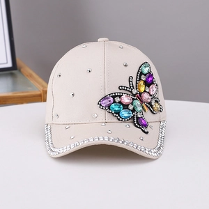 Detailed view of beige baseball cap with colorful rhinestone butterfly and silver brim trim