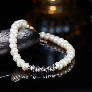 Macro detail of natural freshwater pearl bracelet with silver beads on dark stone