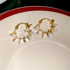 Detail of 18k gold plated geometric earrings with clear crystals on a ceramic plate