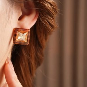 Close-up of a vintage square amber resin earring featuring a yellow inset crystal gemstone