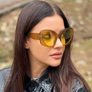 Women's cat eye sunglasses with brown frames and yellow lenses in a stylish outdoor close-up