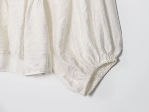 Detailed close-up of white lantern sleeve cuff with elastic smocking and fabric texture