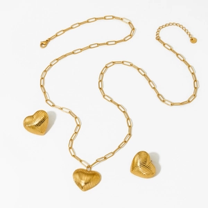 Golden heart pendant necklace and earrings set with textured finish on white background