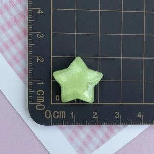 Macro shot of 2cm light green glitter resin star charm for DIY crafts on scale mat