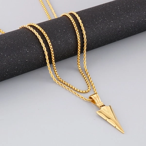 Detail of gold arrow pendant with double layer twisted and box chains on black stand
