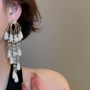 Macro shot of long golden tassel earrings with cascading pearls on a model's ear