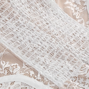 Détail macro de broderie en dentelle blanche élégante avec plis élastiques sur la robe