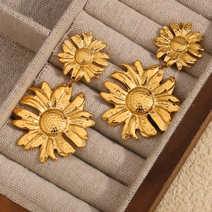 Makroaufnahme von vergoldeten Gänseblümchen-Ohrsteckern mit floralen Details in einer Box