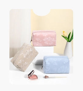 Detailed view of floral jacquard makeup bags in pink, beige, and blue with metal zippers
