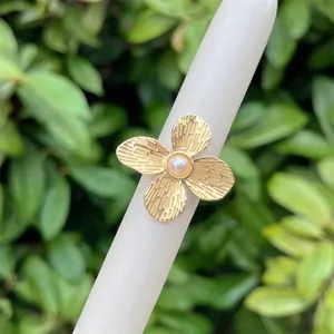 18K gold plated flower ring with striped petals and light pink pearl center on white stand