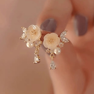 Close-up of golden floral earrings with white pearls and sparkling crystal details