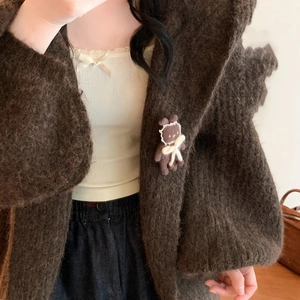 Dettaglio di una graziosa spilla a forma di coniglio marrone su un morbido cardigan