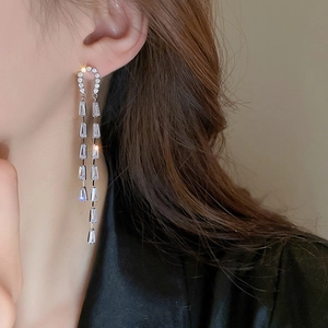 Close-up of elegant silver tassel earrings with rectangular zircon crystals on model