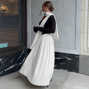 Detailed side view of a black slim fit top and white flowing maxi skirt with a chic scarf