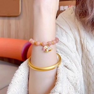 Close-up of pink sunstone beaded bracelet with golden rocking horse charm and matte bangle