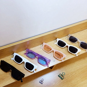 Detailed row of various colored small frame sunglasses on a wooden display stand