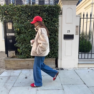 Modische beige Lammfelljacke mit dunkler Paspelierung im trendigen Streetstyle-Look draußen
