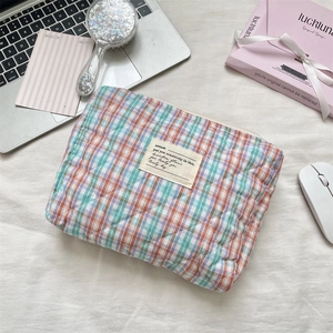 Detail of checkered quilted cotton pouch with top zipper and woven attitude label
