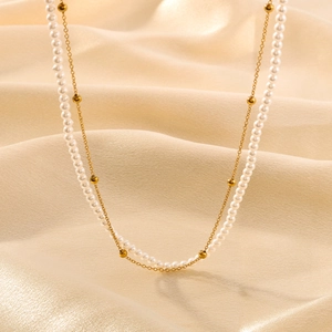 Double layer necklace with gold metal beads and white pearls on champagne silk fabric