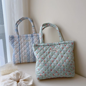 Quilted cotton tote bag with floral patterns and grid design in a minimalist room