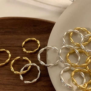 Minimalistische gedrehte Ringe in Gold und Silber auf einem Keramikeinsatz-Tablett