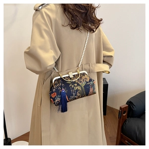 Detailed view of floral embroidery handbag with pearl chain and long blue tassel
