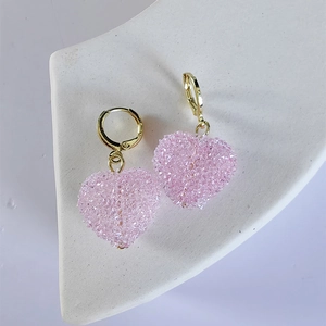 Close-up of pink heart-shaped earrings with glittering crystals and gold accents