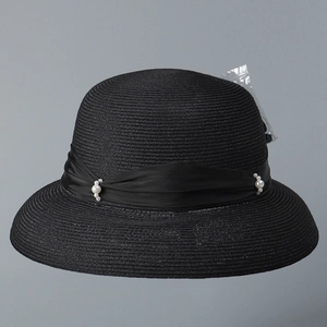 Dettaglio cappello da sole nero intrecciato con nastro di raso e decoro di perle bianche