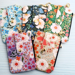 Five floral print leather card holders in various colors with gold zipper and hook detail