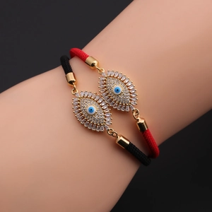 Close-up of red and black woven evil eye bracelets with gold plating and blue crystals
