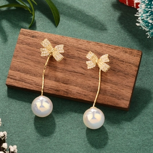 Elegant gold bow earrings with pearls and crystals on a rustic festive background