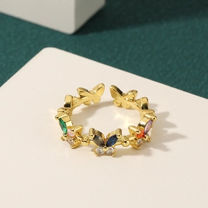 Elegant gold butterfly ring with colorful gemstone micro-inlay on a white textured surface