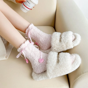 Détail de chaussettes en molleton corail rose avec nœud satin et chaussons blancs