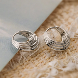 Chic silver ribbed hoop earrings with multi-layered design on cozy knit background