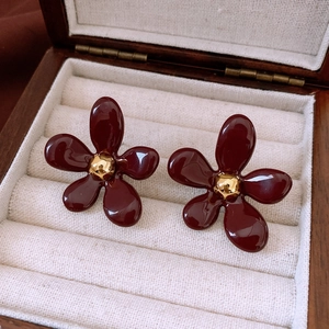 Gros plan détaillé de boucles d'oreilles fleurs en résine bordeaux dans un écrin en bois